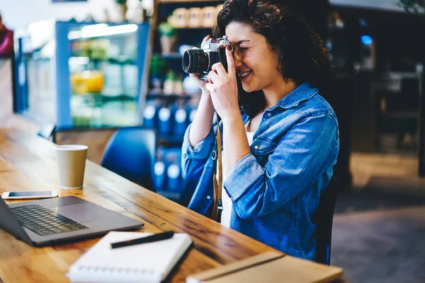 喫茶店でリモートワークをしながらヴィンテージカメラで写真を撮る熟練した女性写真家 カフェで余暇にレトロな道具を使って写真を撮ることに100万人の女性の焦点 — ストック写真