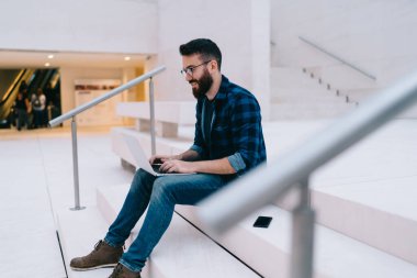 Kafkasyalı erkek programcı internet sitesini taramak ve uygulama yüklemek için 4g interneti kullanarak dizüstü bilgisayarında yazılım güncellemesi ile uzaktan çalışıyor. Optik göz giyimi blogunda yetenekli hipster adam.