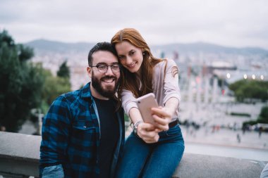 Mutlu eş 20 'li yaşlarda cep telefonu kamerasında gülümsüyor birlikte seyahat etmenin keyfini çıkarıyor, komik erkek ve kadın en iyi arkadaşlar mobil uygulama ile video bloğunu etkiliyor