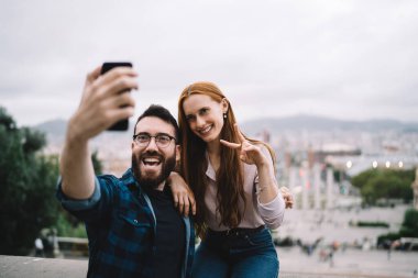 Neşeli eş 20 'li yaşlarda cep telefonu kamerasına gülümseyen birlikte seyahat etmenin keyfini çıkaran neşeli erkek ve kadın en iyi arkadaşlar mobil uygulama ile video bloğunu etkiliyor.