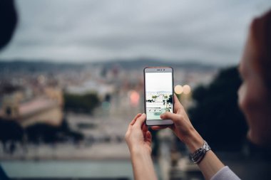 Tatillerde şehir manzarasına tıklamak için akıllı telefon kamerası kullanan kadın blogcunun arka planı, mobil uygulama üzerinden video bloğu etkilemek için 4G internete bağlanan tanınamaz kadın