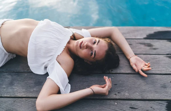 High Angle Sensual Female White Top Lying Poolside Looking Camera — Stockfoto