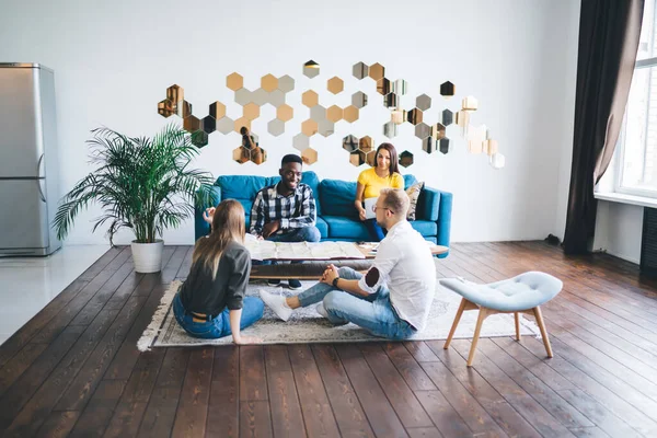 Full Length Multiracial Friends Sitting Surrounding Coffee Table Covered Map — Stock Photo, Image