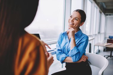 Happy female partners communicating about project planning productive collaboration, cheerful businesswoman laughing and smiling during friendly conversation with colleague in office interior