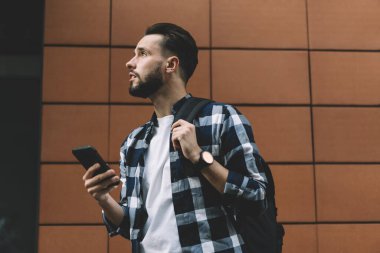 Düşüncelere dalmış bin yıllık hippi adam 4G internet bağlantısını ve akıllı telefon aygıtı için en iyi operatör tarifesini düşünüyor.