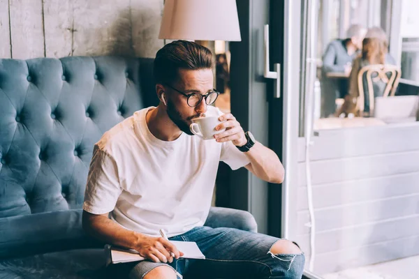 Ung Mannlig Student Elektroniske Ørepropper Som Drikker Koffein Som Bruker – stockfoto