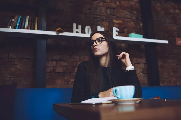 カフェテリアでおいしいコーヒーを飲みながらテーブルに座っている間 目を離して見てカジュアルな服を着た若い女性 — ストック写真