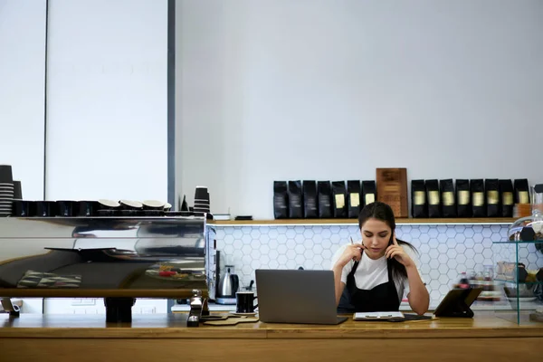 コーヒーショップでサービスを提供するための技術を使用してオンライン注文をチェック携帯電話で話すプロの白人女性バリスタ — ストック写真