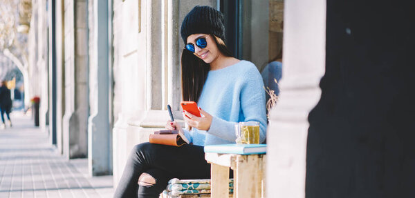 Cheerful hipster girl with personal diary planning organisation of weekend leisure checking text in smartphone