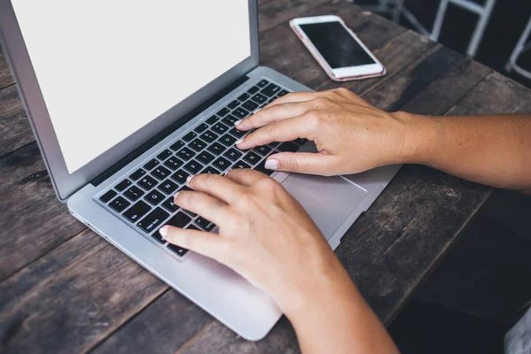 From above of anonymous crop lady with manicured nails and tattoos typing text on laptop while working at workplace