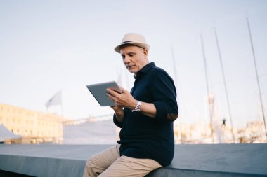 İnternet sitesinde modern dokunmatik ped ile sosyal medya ağı kuran beyaz erkek kıdemli turist 