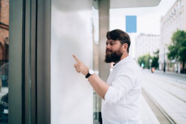 Megapolis 'teki otobüs durağındaki boş beyaz ekran üzerinde siyah saçlı yetişkin adamın yan görüntüsü.