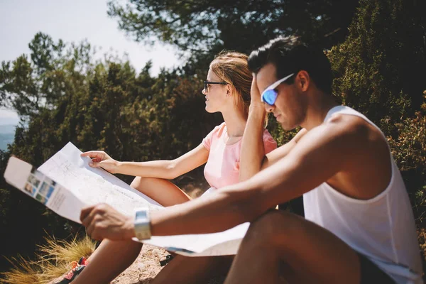 年轻男女游客穿着休闲装坐在山上 在阳光明媚的夏日探索地图的侧视图 — 图库照片