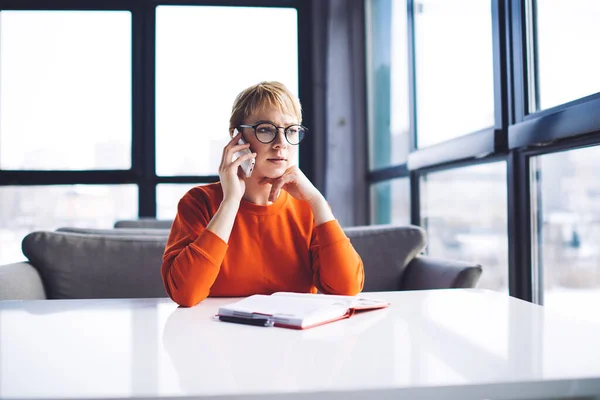 Joven Freelancer Femenina Enfocada Jersey Naranja Gafas Teniendo Conversación Teléfono —  Fotos de Stock