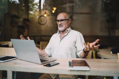 Ciddi erkek girişimci, uzak bir iş sırasında dizüstü bilgisayarla web sayfalarındaki bilgileri analiz ederken şaşkın hissediyor