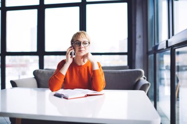 Uzaktan kumandalı kadın çalışanlar ellerini çenelerine uzatıp iş yaparken cep telefonlarıyla konuşuyorlar.