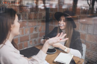 İyi giyimli, yaratıcı çalışma alanında oturan ve iş projesiyle ilgili iş arkadaşlarıyla konuşan bir kadının cam görüşü sayesinde.