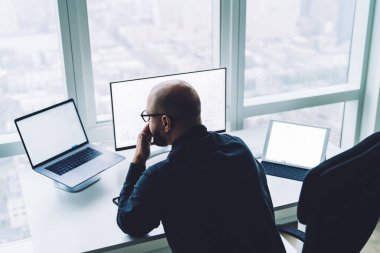 Multimedya araçları ve modern çalışma alanındaki pencere yakınlarındaki netbook 'ta verileri analiz ederken tanınmayan bir erkeğin yüze dokunuşunu yukarıdan izlemek