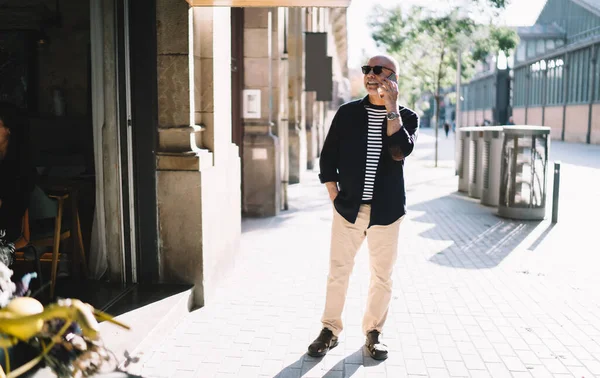  Modayı takip eden emekli adam dijital cep telefonu aygıtıyla konuşuyor ve iletişim kuruyor.