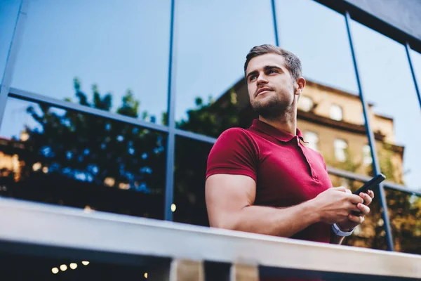 Pensive Young Hipster Polo Shirt Browsing Smartphone Looking Away Modern — Stock Photo, Image