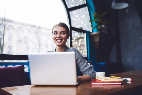 Optimistic Female Freelancer Toothy Smile Looking Away While Sitting Table — Stockfoto