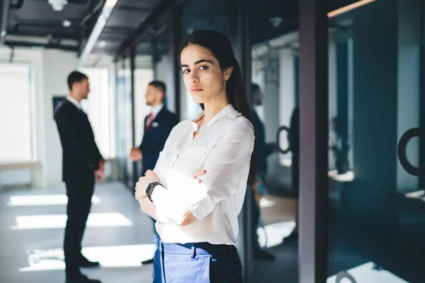 身穿白衬衫 一头长长的黑发 心烦意乱的年轻女企业家手挽手站在办公室大厅的侧影 — 图库照片