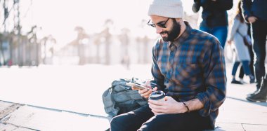 Seyahat gezisi sırasında sosyal ağlara paylaşmak için seyahat yayınının metnini yazan Ortadoğu sırt çantası taşıyıcısı