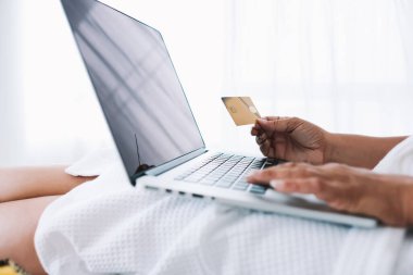 Bornozlu anonim bir kadın online alışveriş için dizüstü bilgisayar kullanıyor. Kuala Lumpur 'da internet üzerinden mal almak için kredi kartı numarası yazıyor.