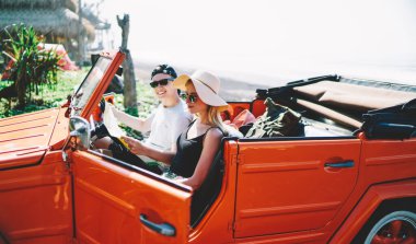 Haritayla arabada oturan mutlu bir adam, yaz tatilinde kapıyı açan bir kadın ve güzergah seçiyor.