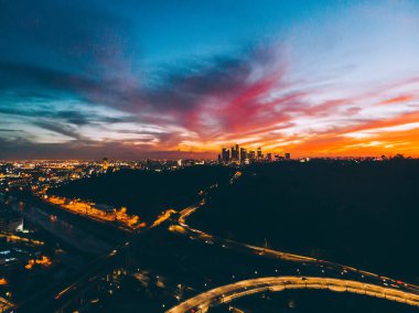Los Angeles, ABD 'de alacakaranlıkta şehir merkezinde parlayan ışıklar ve trafik kavşağı olan çağdaş şehrin hava görüntüsü