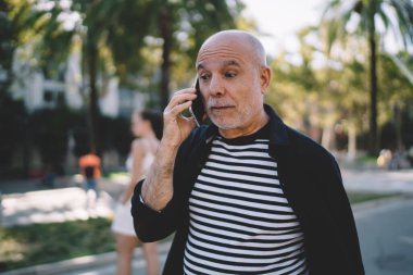 Cep telefonu uygulaması ile iletişim kurmak için gezen kablosuz internet kullanan emekli bir erkek.