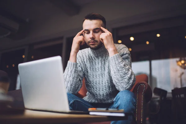 Focused Young Man Casual Clothing Rubbing Temples While Looking Screen — Stockfoto