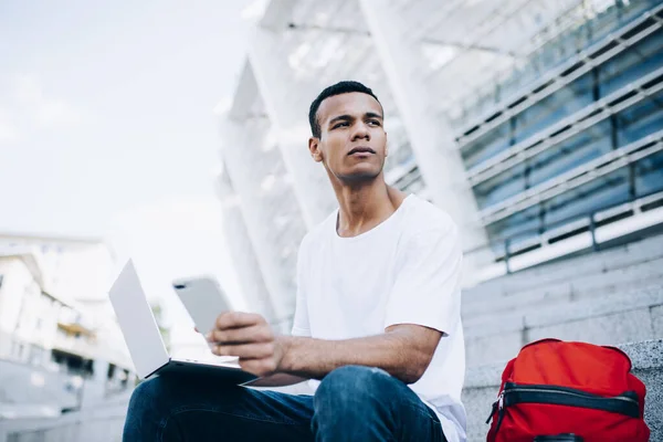 Low Angle Pensive African American Man Freelancer Browsing Netbook Smartphone — Fotografie, imagine de stoc