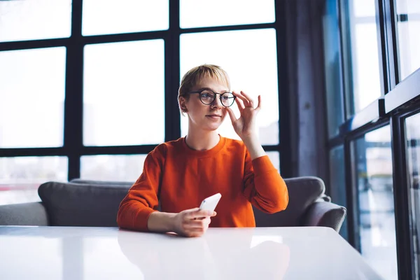 Young Female Casual Clothes Sitting Table Mobile Phone Touching Eyeglasses — Stockfoto