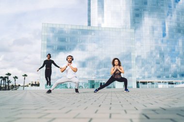 Erkek ve kadın sporculardan oluşan kararlı bir ekip gökdelen arka planında antrenman yapıyor.