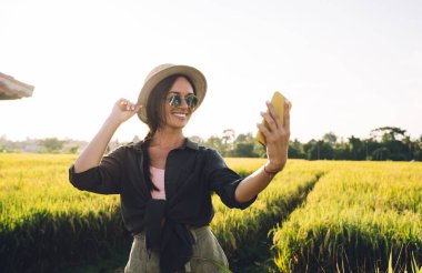 Dişli hippi blogcu Phuket 'teki pirinç tarlalarını ziyaret ederken cep telefonu kamerasına gülümsüyor.