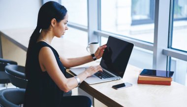 Yoğunlaştırılmış kadın uzaktan çalışan netbook 'un yan görüntüsü ve çağdaş iş yerinde masada otururken ekrana bakmak