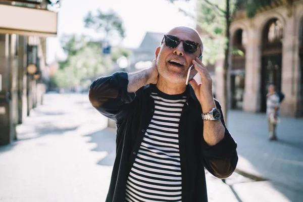  Modayı takip eden emekli adam dijital cep telefonu aygıtıyla konuşuyor ve iletişim kuruyor.