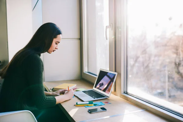 Side View Young Focused Female Sweater Sitting Windowsill Netbook Smartphone — Stockfoto