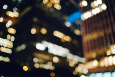 Bokeh şehrinin arka planında modern şehrin karanlık caddelerindeki büyük kulelerin pencerelerinden parlak ışıklar görünüyor.