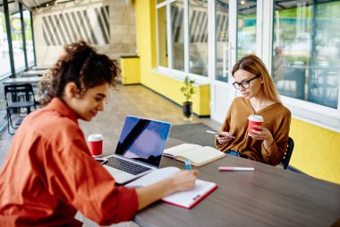 Not defterine notlar yazan mutlu etnik kadın ve üniversite için çalışırken kahve alıp sörf yapan düşünceli bayan öğrenci.