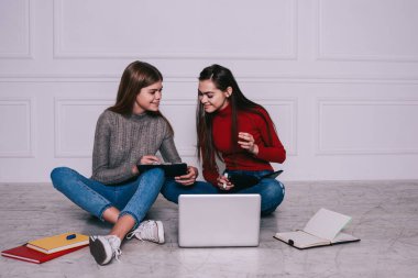 Genç, mutlu, uzaktan kumandalı bir kadın, bacak bacak üstüne atarak yerde oturuyor ve ışık odasında çalışırken panoda meslektaşlarına kâğıtları gösteriyor.