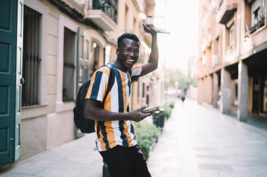 Caddede iletişim kurarken kameraya gülümseyen klasik gözlüklü neşeli seyahat blogcusunun yarım boy portresi