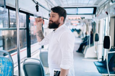 Gündüz vakti durmayı beklerken trende dikilip bakışlarını kaçıran genç bir adam.