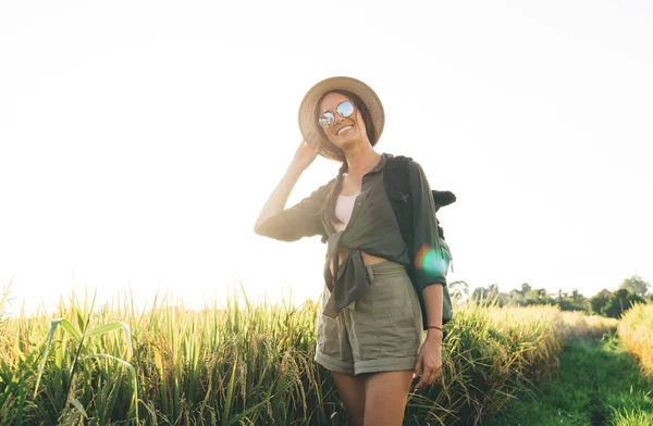 Kırsal kesimde yaz mevsiminde kameraya gülümseyen neşeli bayan turistin yarım boy portresi.