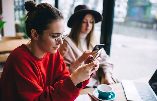 Kafeterya projesinde çalışırken, bir fincan çay içip, akıllı telefonları karıştıran gündelik kıyafetli genç bayan arkadaşlar.