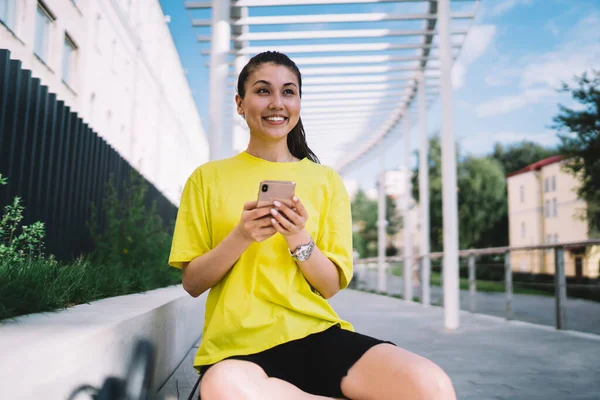 Genç ve neşeli Asyalı kadın sörf ağı. Cep telefonuyla. Ve yazın şehir caddesinde bankta otururken başka yere bakıyor.