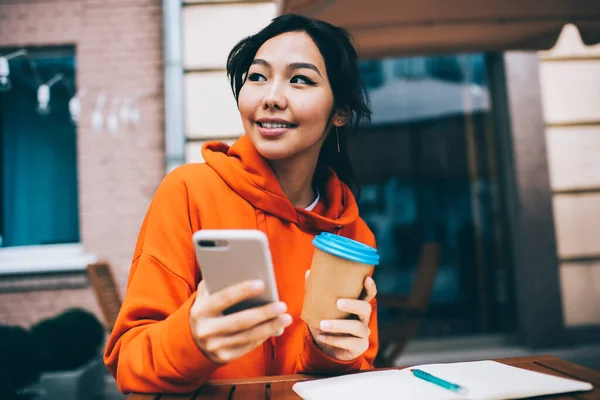 Felice Freelance Asiatica Guardando Altrove Mentre Gode Caffè Utilizzando Telefono — Foto Stock