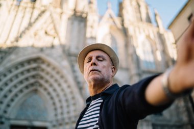 Yaşlı beyaz nüfuzlu, 60 yaşında. Tarihi kenti keşfetmek için yapılan solo yolculuk sırasında seyahat videosu çekiyor.