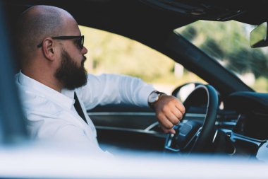 Sıcak hava koşullarında işe giderken, kendine güveni tam bir erkek sürücünün kol saati ile otomobilde oturması yan görünüm